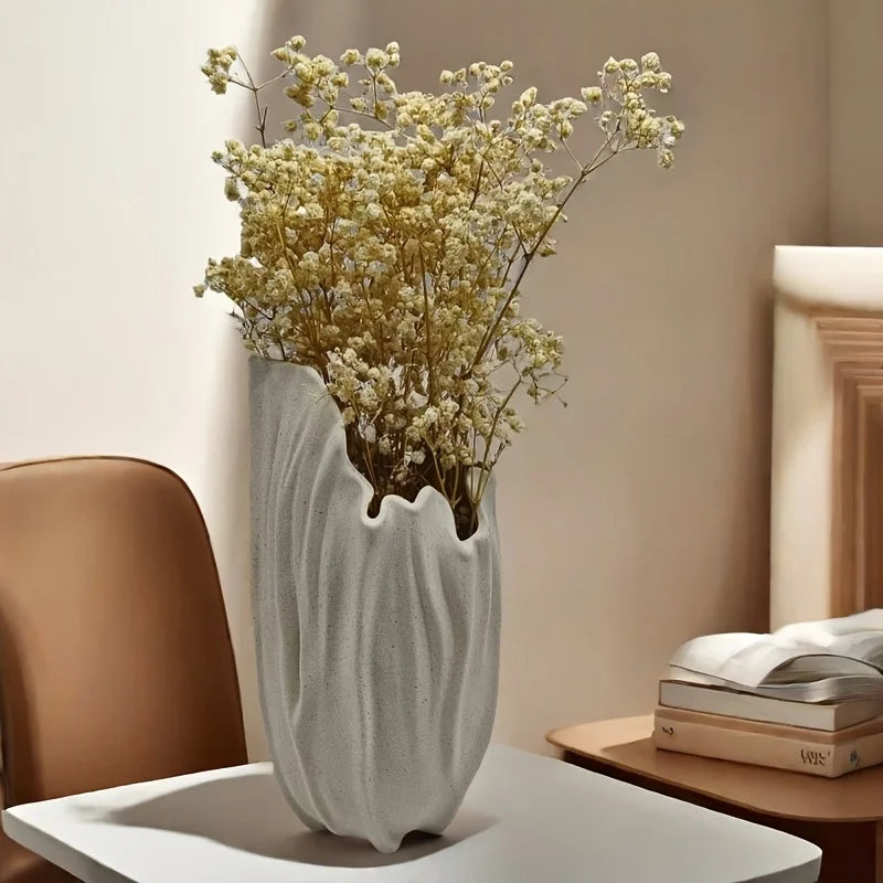 Decorative bohemian vase with dried flowers on a table in a room setting.