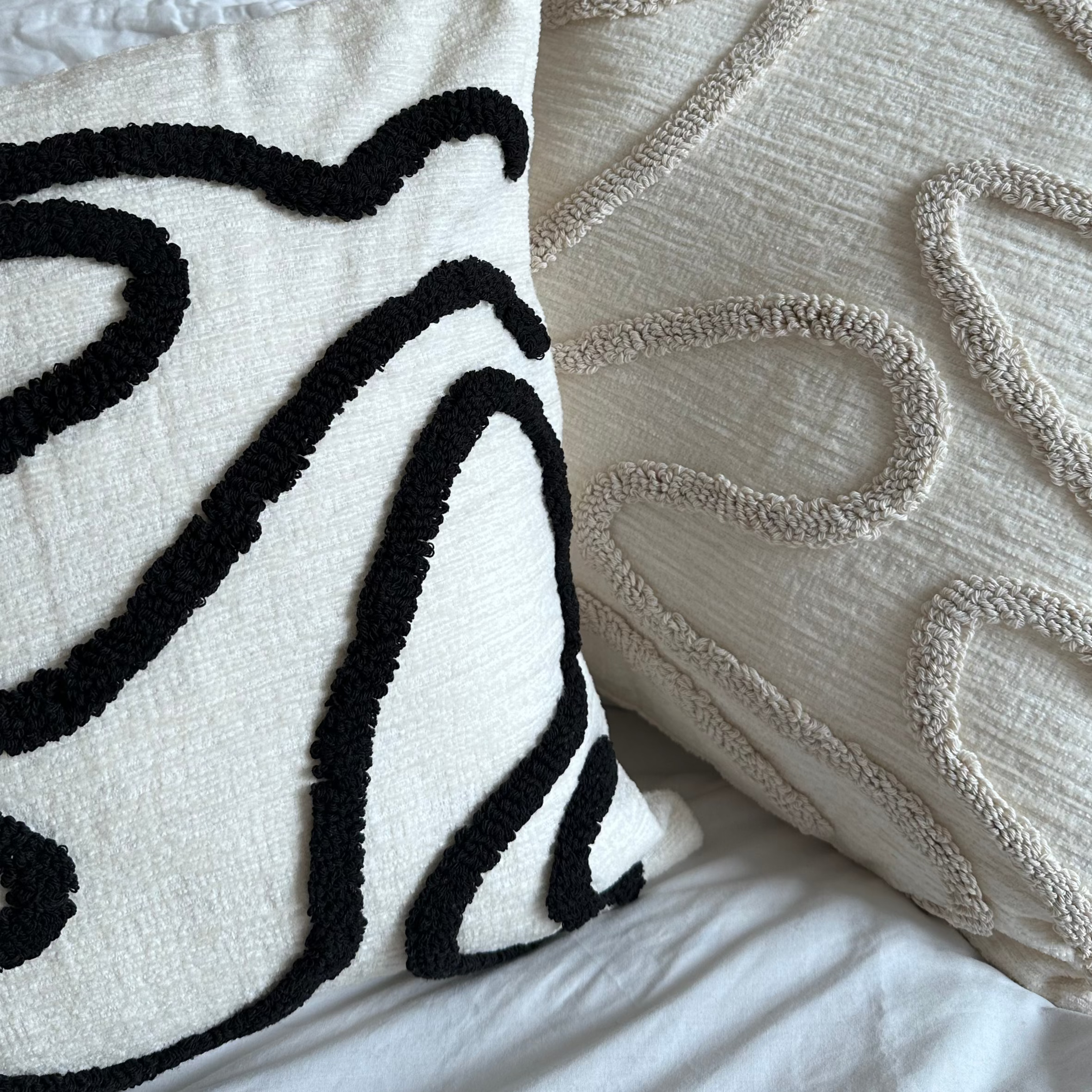 Two decorative pillows on a bed with a wooden headboard.