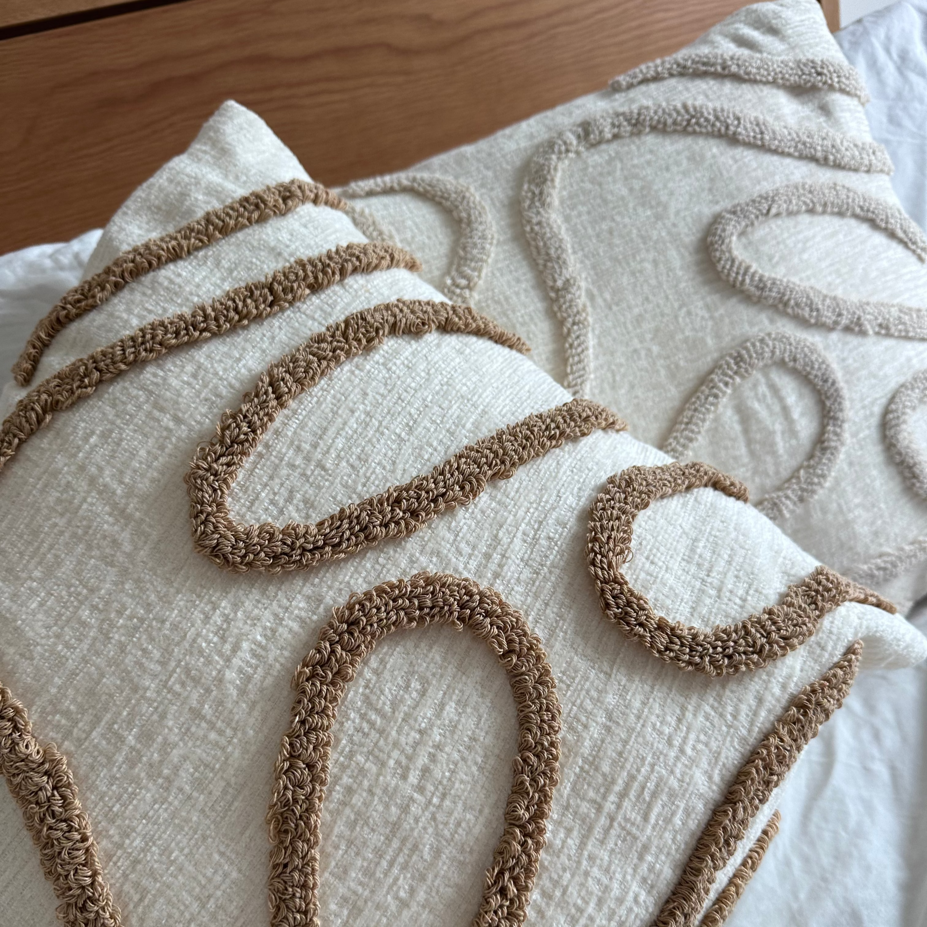 Decorative pillows with brown and beige patterns on a bed.