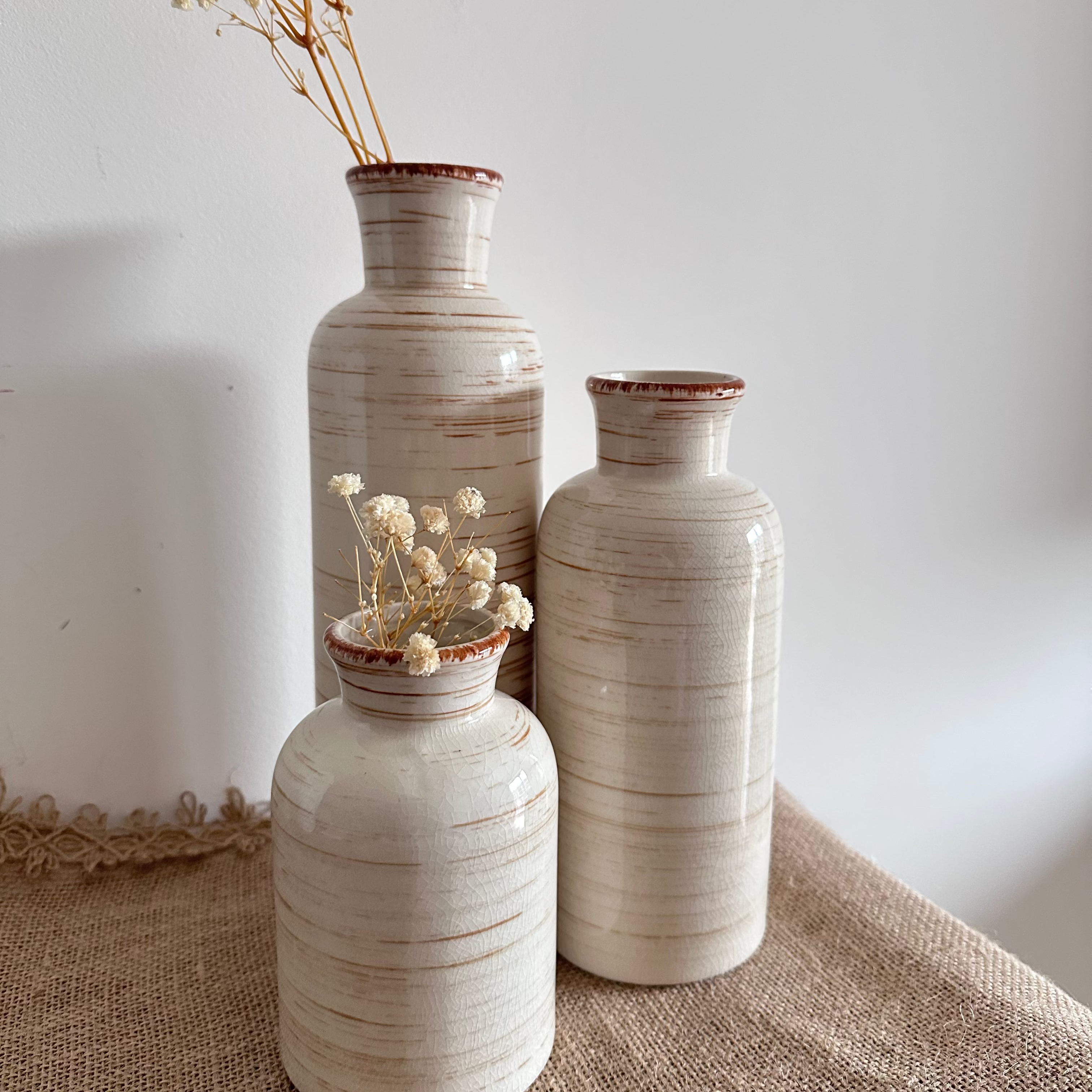 Three ceramic vases of different sizes on a textured surface with a plain background