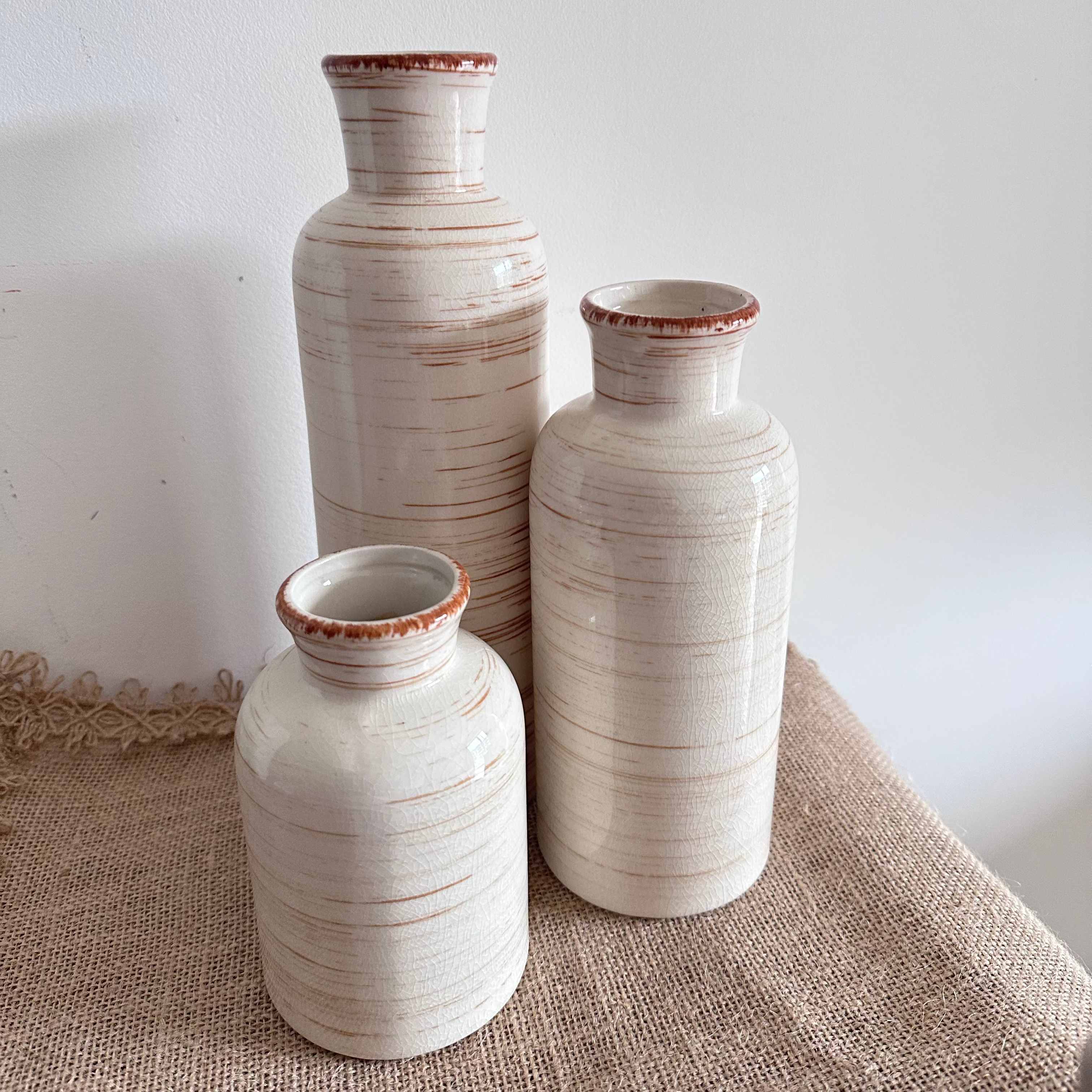 Three ceramic vases of different sizes on a textured surface with a white background