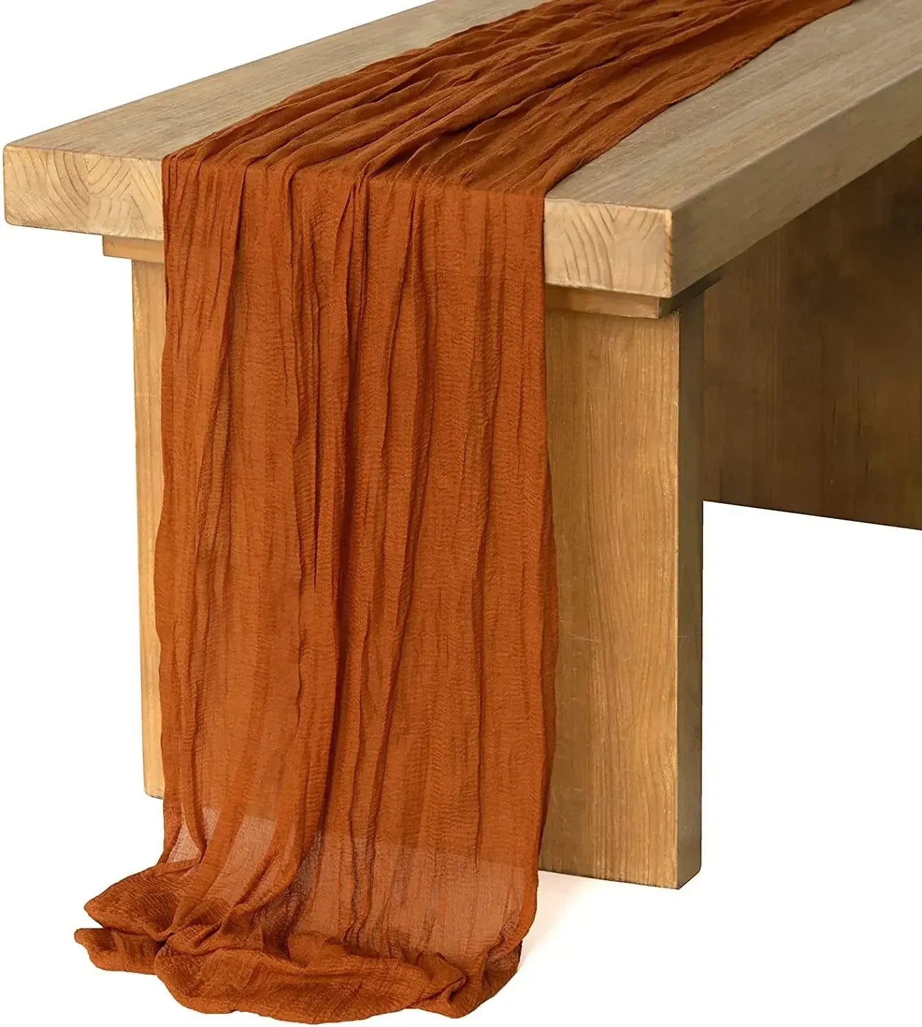 A brown cheesecloth table runner with a rustic design, laid out on a wooden dining table.