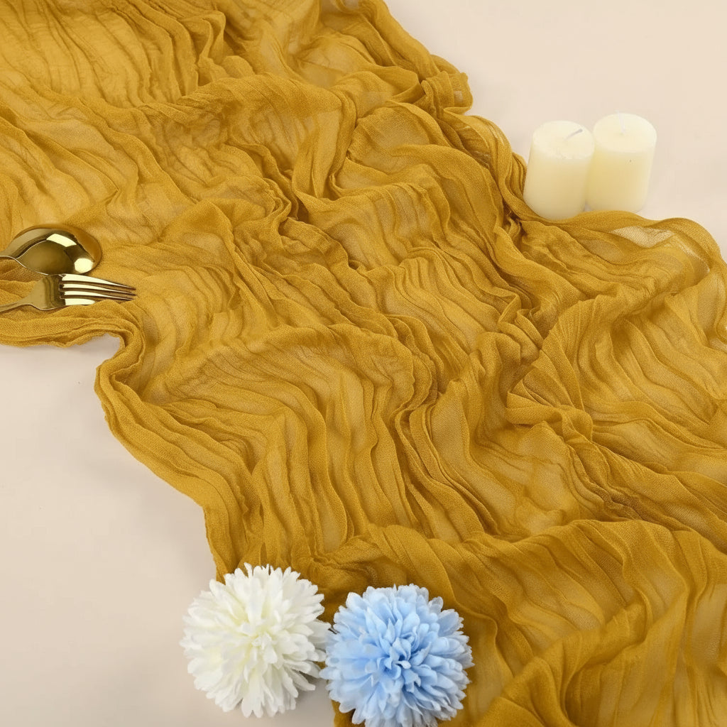 A close-up of a mustard cheesecloth rustic table runner draped on a white surface.