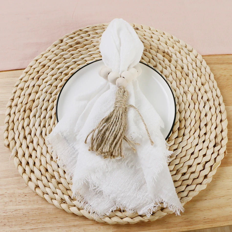 A white cotton napkin is draped over a woven round basket, with a decorative bow added to the top of the napkin.