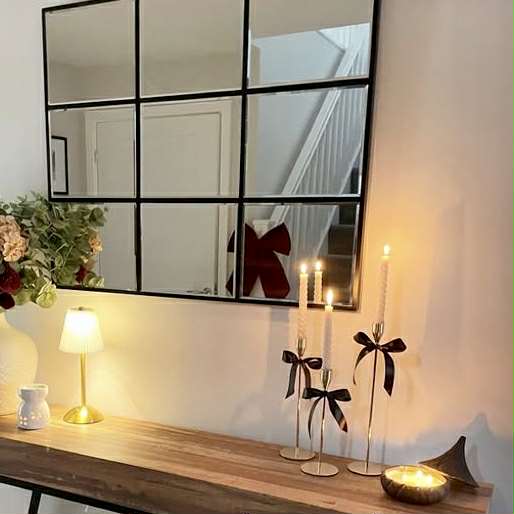 Decorative setup with gold candle holders, a lamp, and flowers in front of a large mirror.