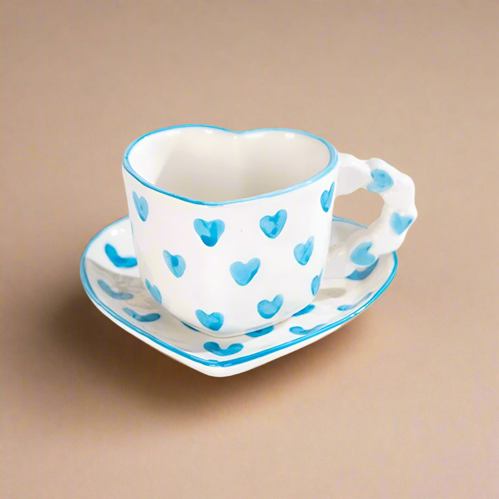 Ceramic heart-shaped mug with blue, hand-painted heart patterns.