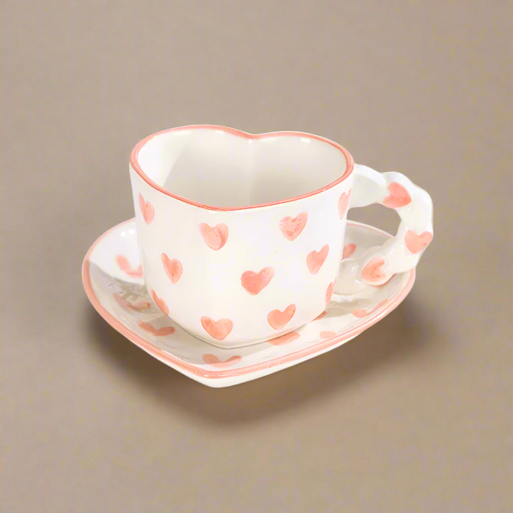 Ceramic heart-shaped mug with pink, hand-painted heart patterns.