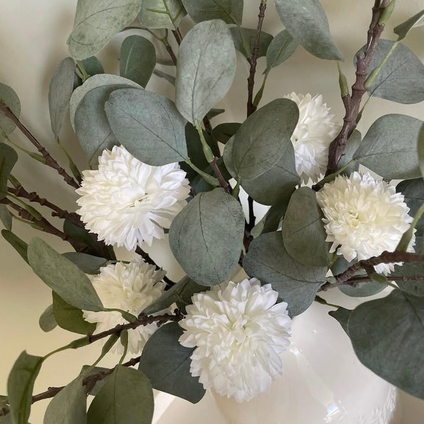 Artificial greenery with white hydrangea flowers on a neutral background