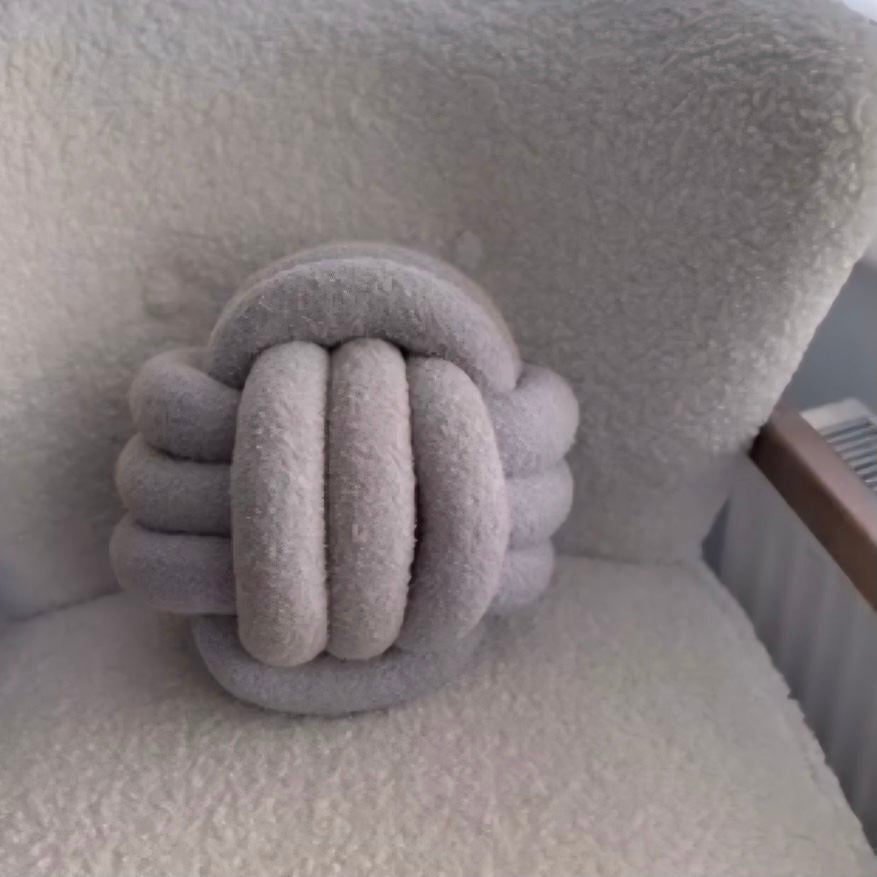 Light Grey knotted pillow on a textured surface