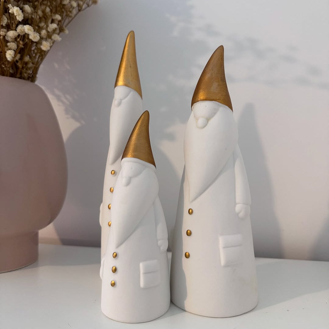 Three decorative figurines with gold accents on a white surface.