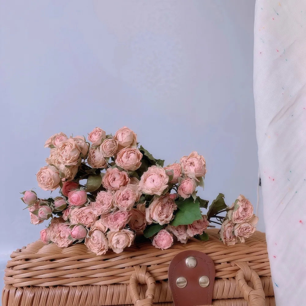 Bouquet of dried pink flowers on a wicker basket with a light blue background