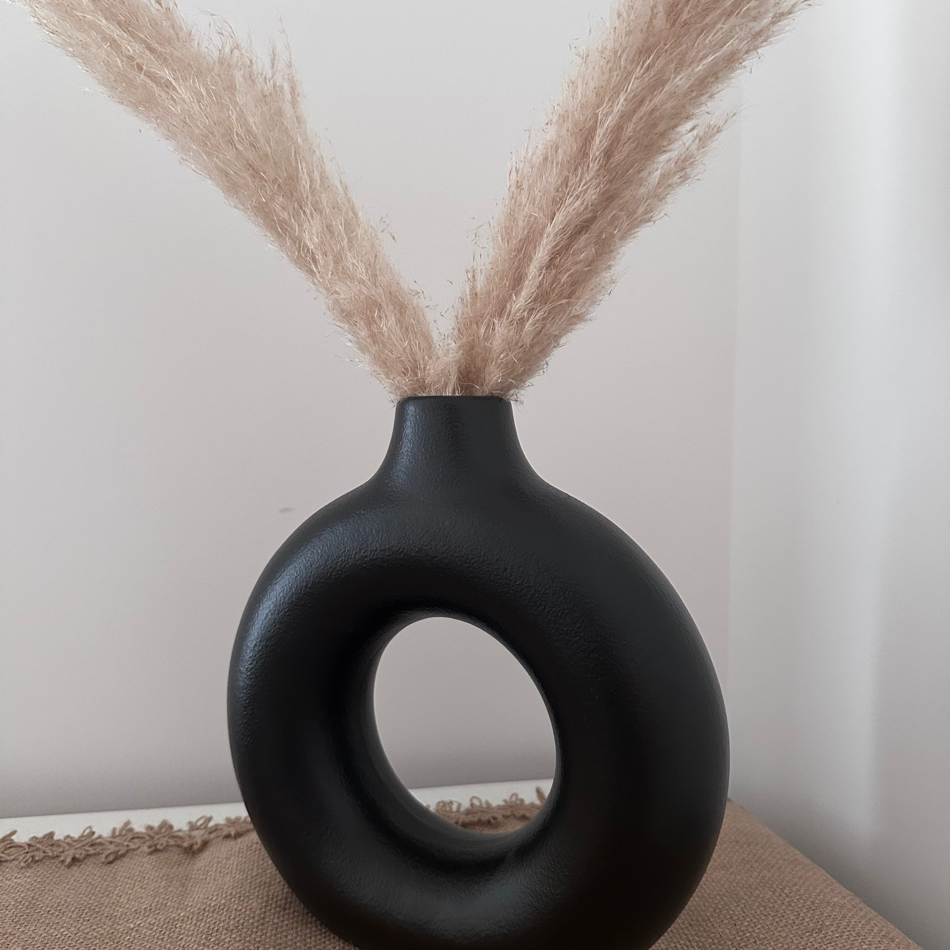 Black nordic circular vase with dried pampas grass on a neutral background