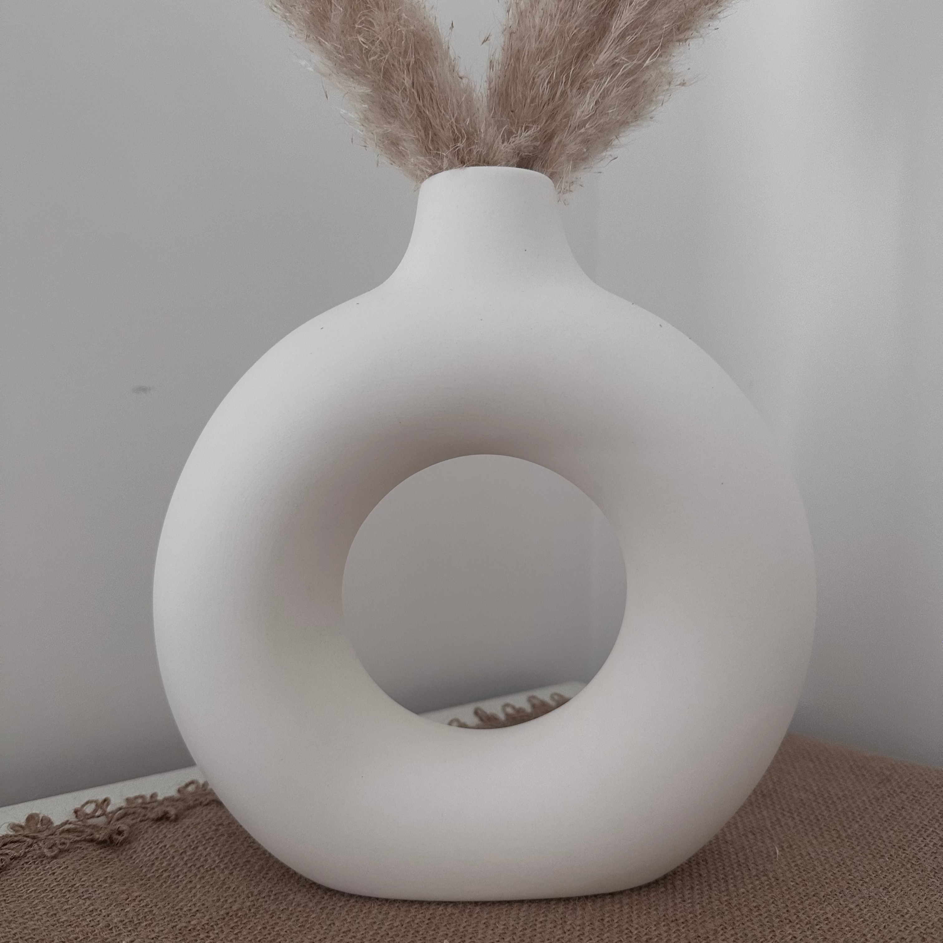 White decorative vase with a circular design on a textured surface