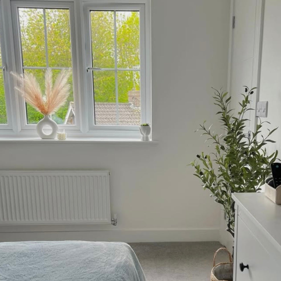 Modern bedroom featuring a white Nordic circular vase on a windowsill. The vase contains dried flowers.
