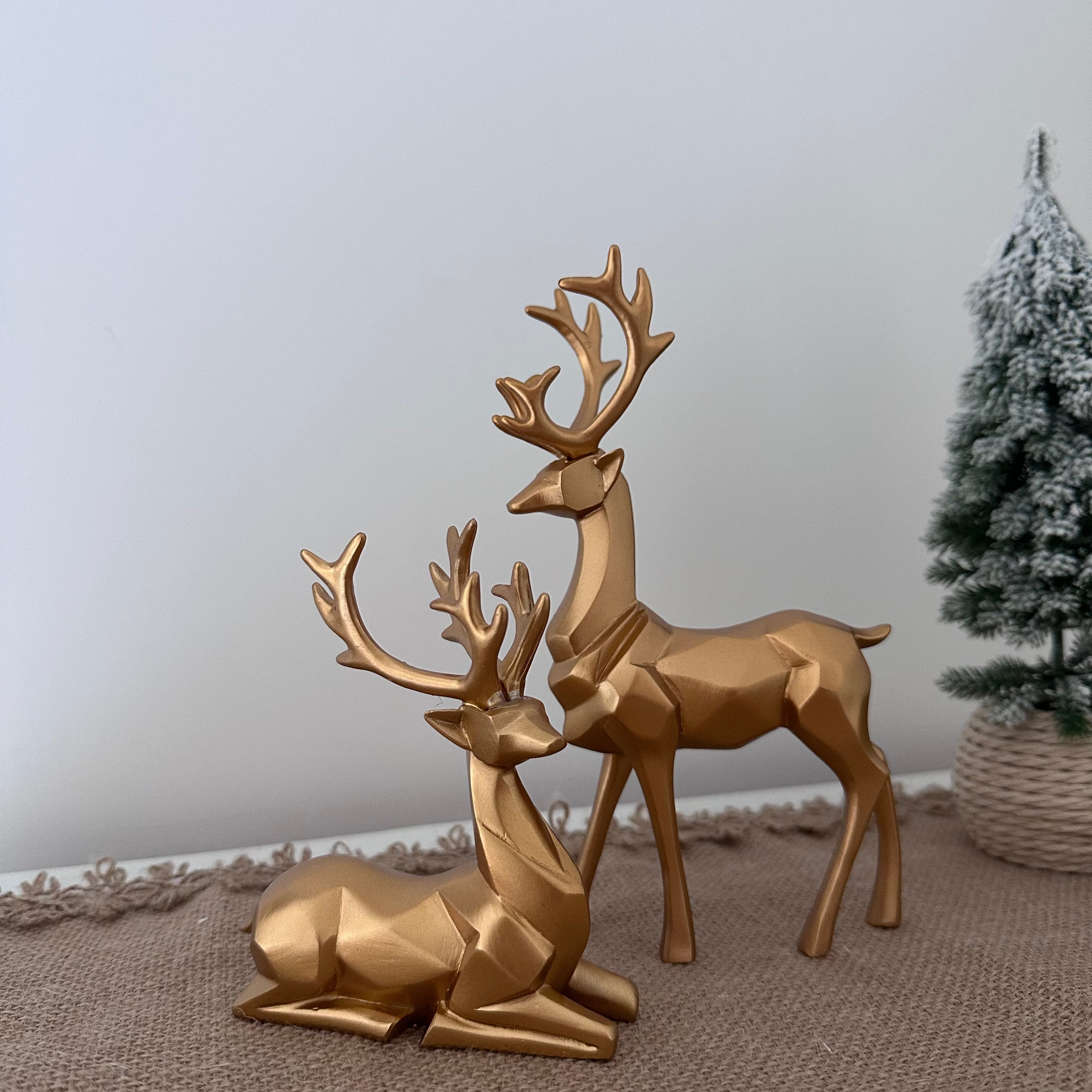 Gold deer figurines on a textured surface with a neutral background