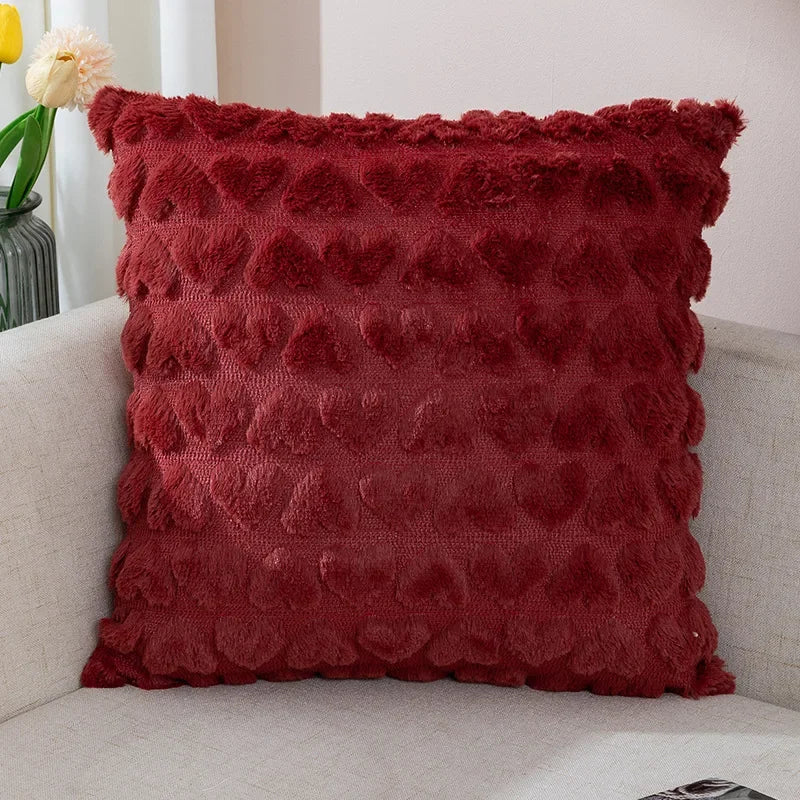A red plush love heart pillow cover on a couch, with a textured pattern creating a heart shape.