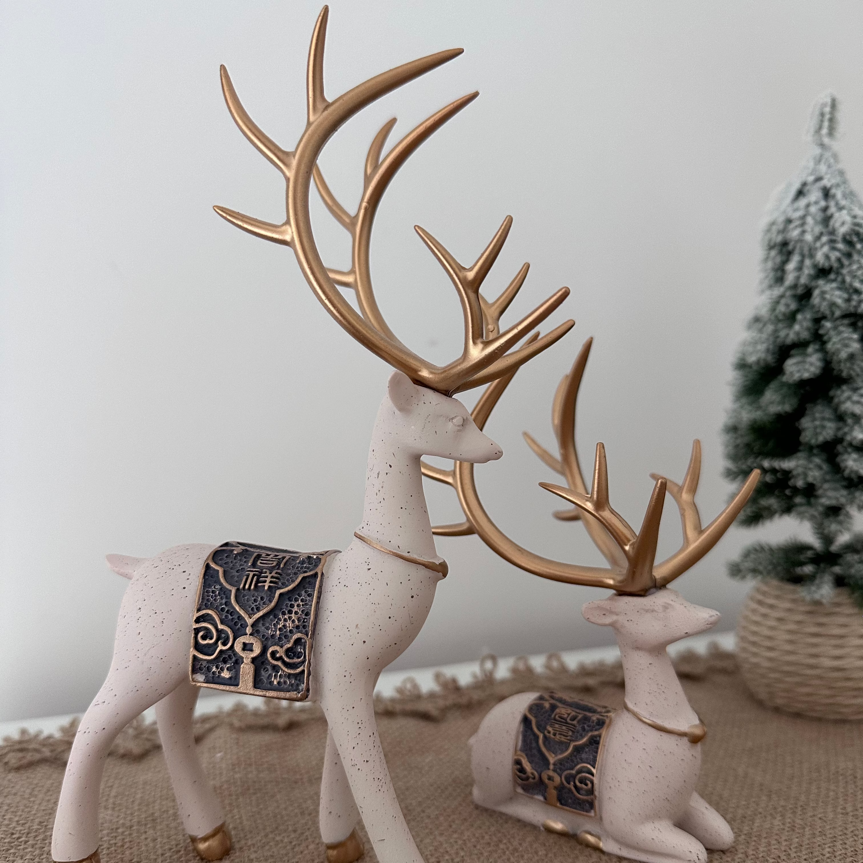 Decorative reindeer figurines with gold antlers on a textured surface.