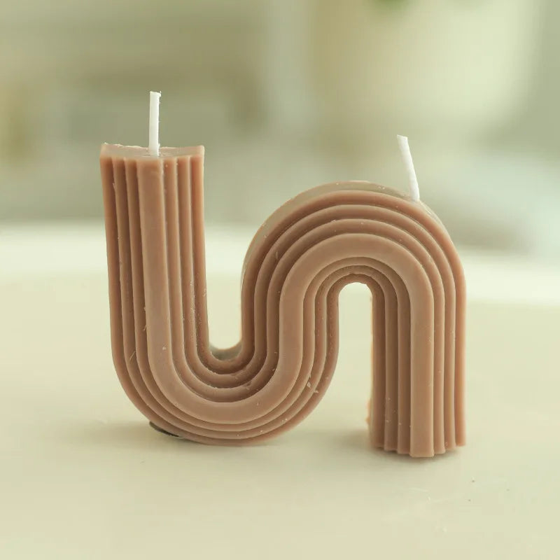 A decorative S-shaped candle made from soy wax in the colour dark brown