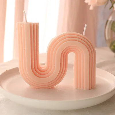 A decorative S-shaped candle made from soy wax in the colour light pink