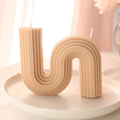 A decorative S-shaped candle made from soy wax in the colour milk tea