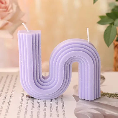 A decorative S-shaped candle made from soy wax in the colour purple