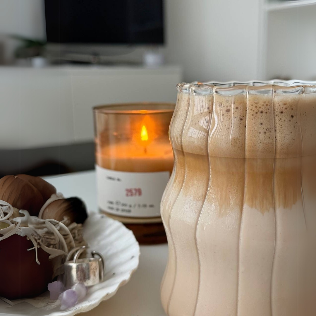 Glass of iced coffee with a candle and decorative items on a table