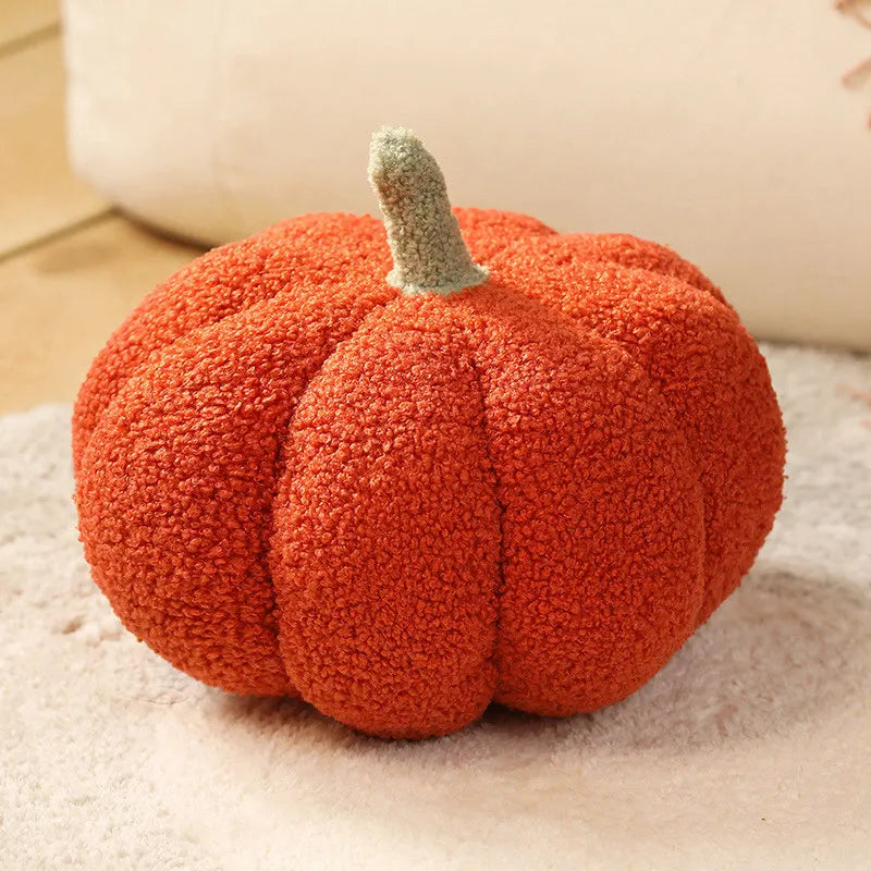 Deep orange textured pumpkin cushion with a green stem on a beige blanket