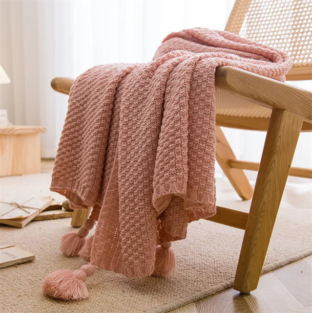 A pink Nordic waffle blanket draped over a chair in a minimalist room setting.