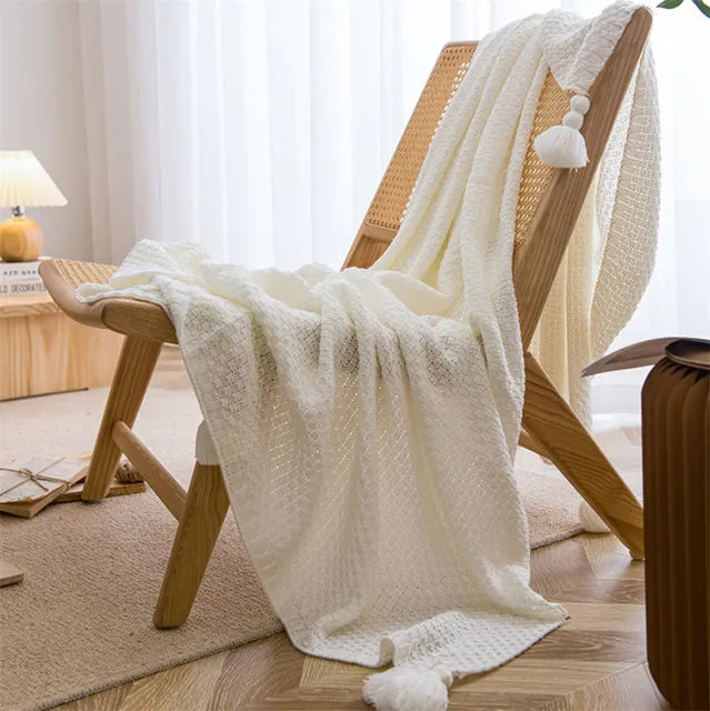A white Nordic waffle blanket draped over a chair in a minimalist room setting.