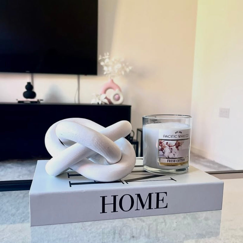 Decorative knot sculpture on a 'HOME' box with a candle in the background