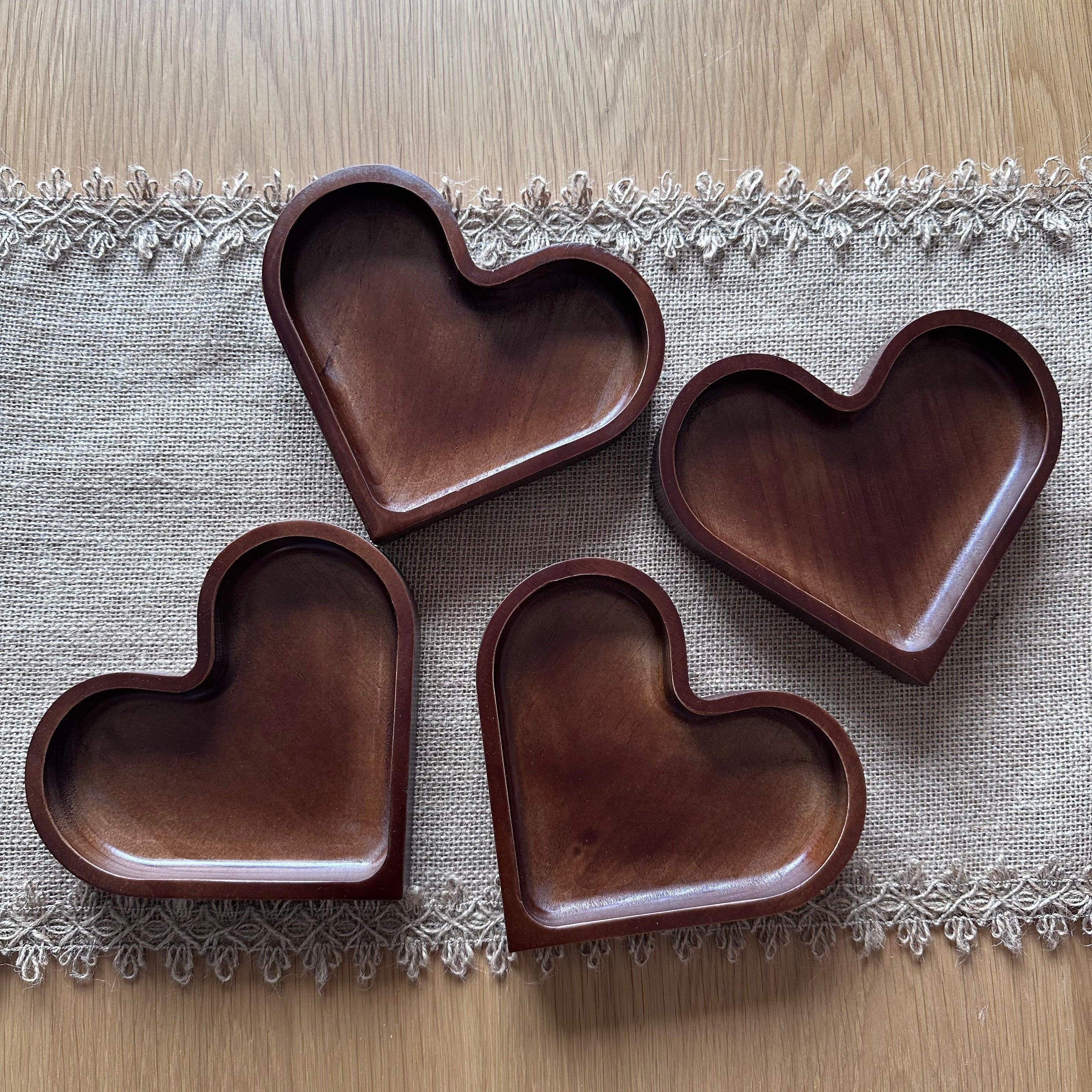 Four heart-shaped wooden trays on a textured fabric surface