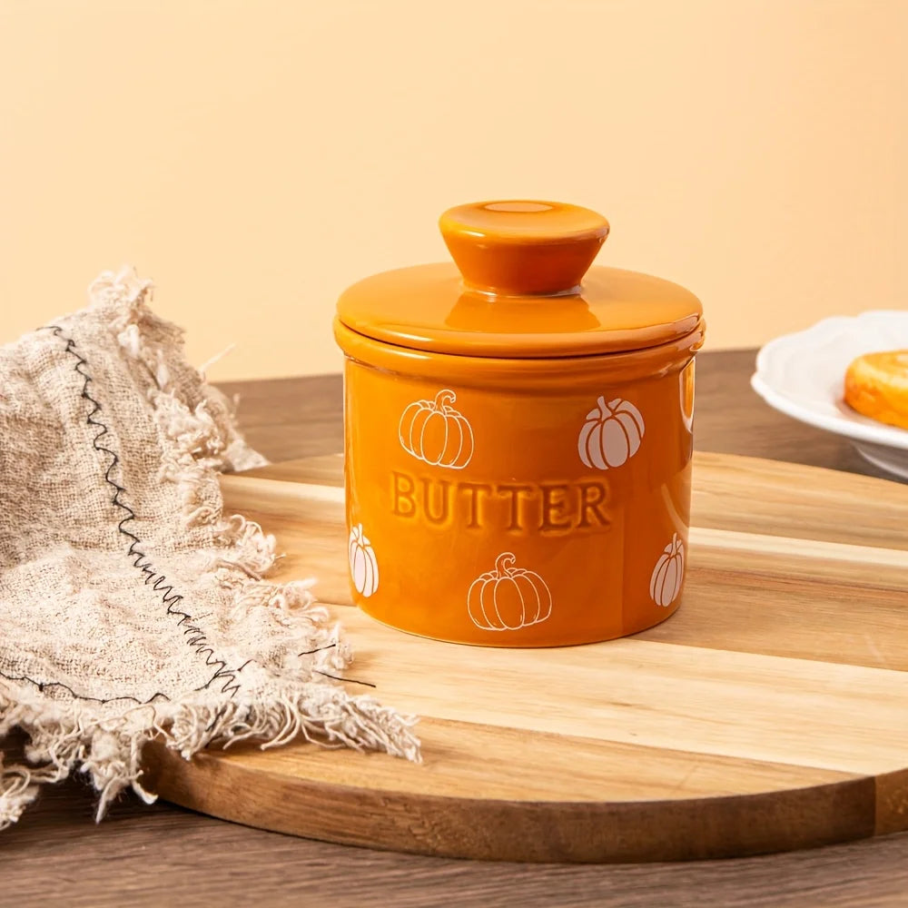Orange butter container with pumpkin design on a wooden surface