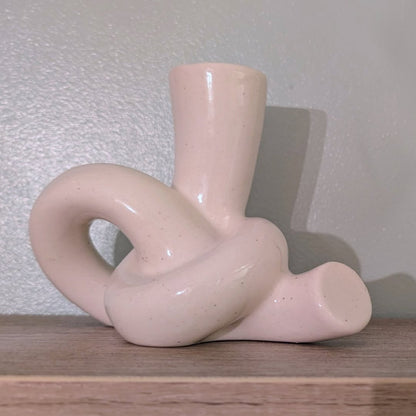 white ceramic candle holder on a wooden surface with a light gray textured wall background