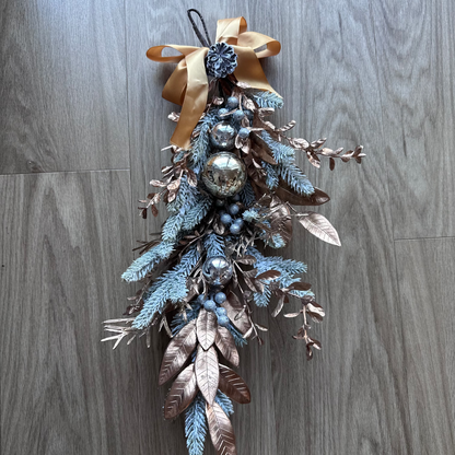 Decorative wall hanging with branches, berries, and a bow on a wooden surface