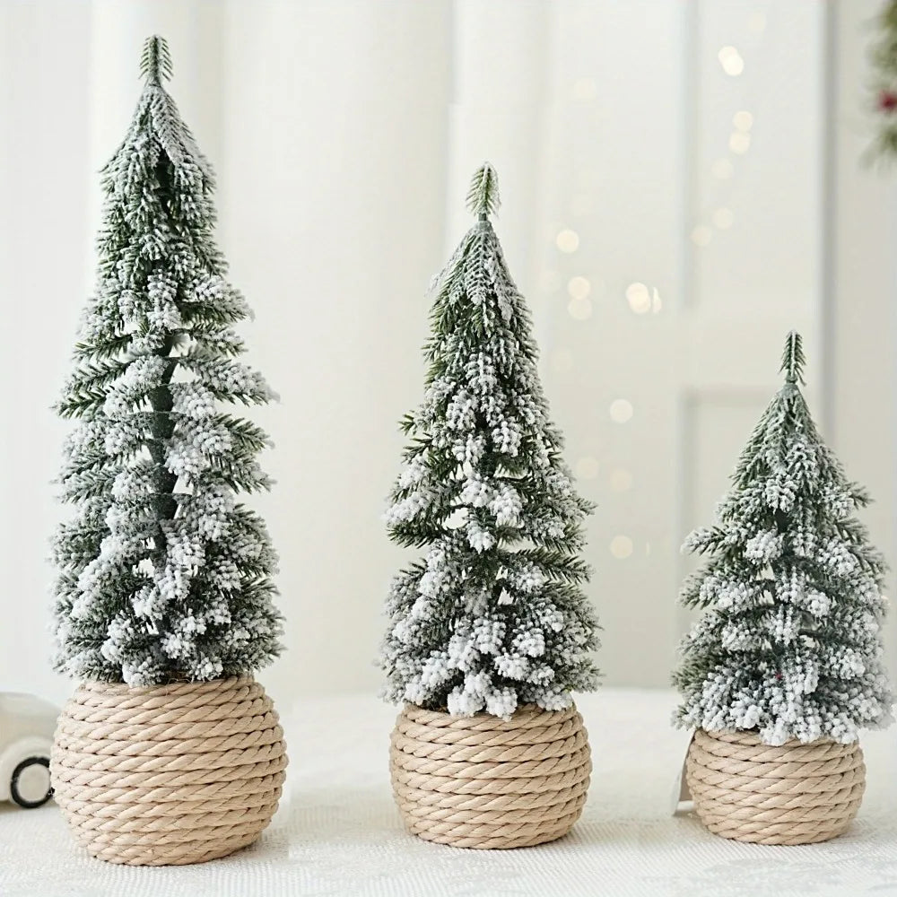 Three artificial snowy Christmas trees in different sizes with a rustic linen, burlap wrapped base, displayed on a table with a festive background.