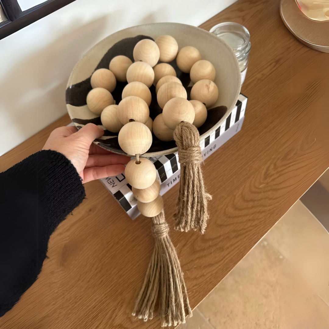 Decorative bead garland with hemp tassel styled in a wooden bowl. 