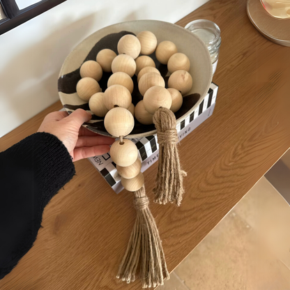 Decorative bead garland with hemp tassel styled in a wooden bowl. 