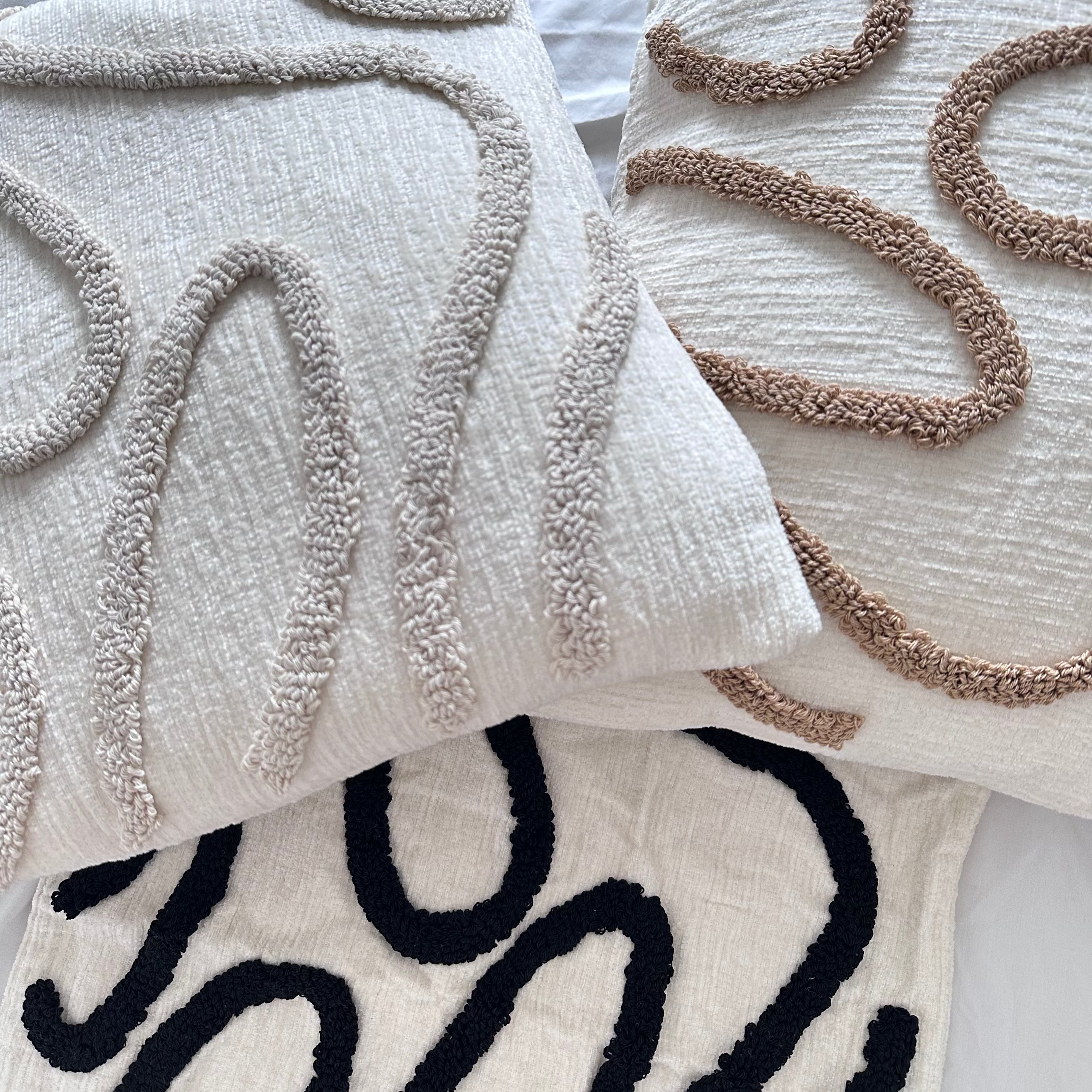 Textured throw pillows with abstract patterns on a light background