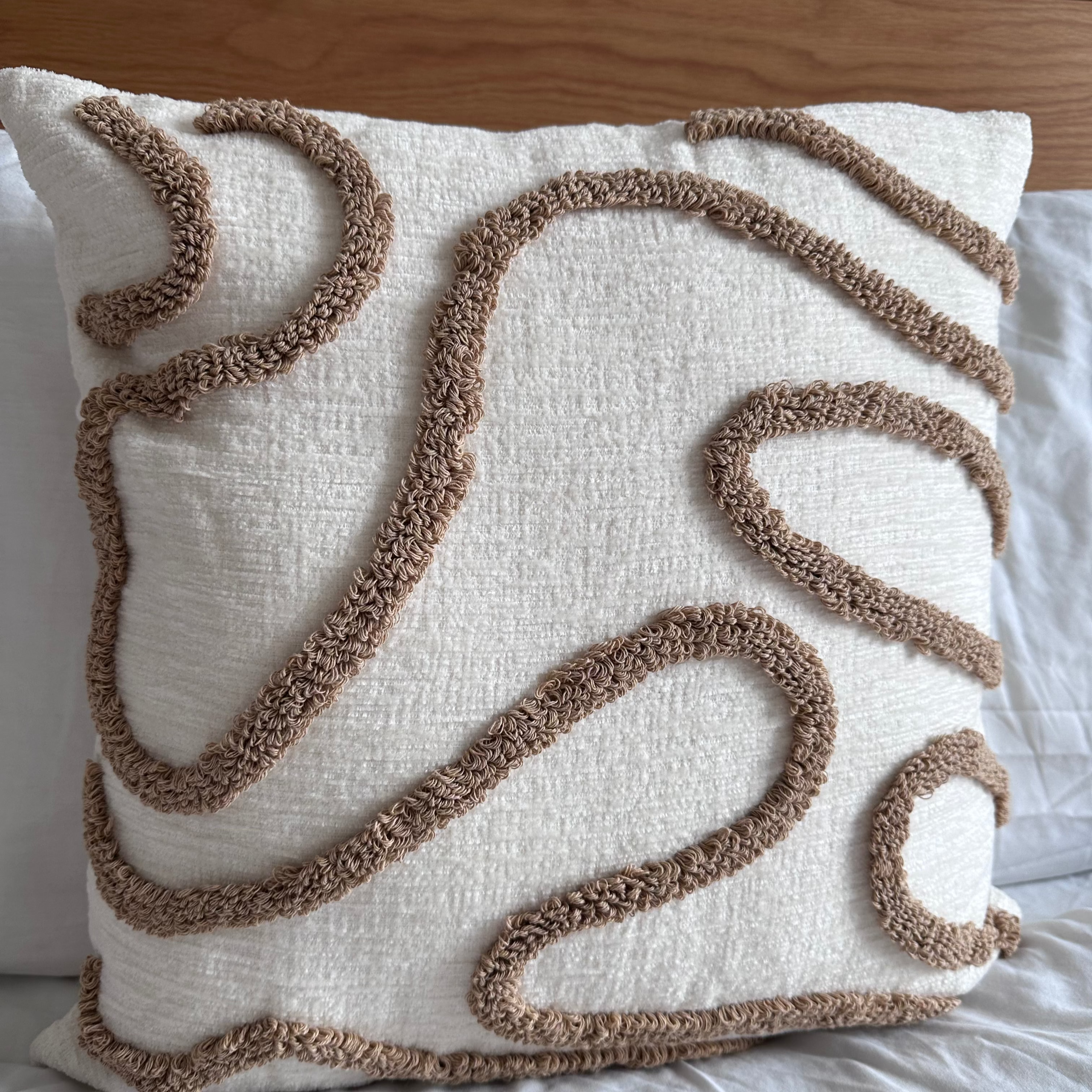 Decorative pillow with brown abstract patterns on a bed