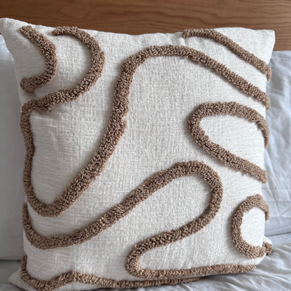 Decorative pillow with brown abstract patterns on a bed