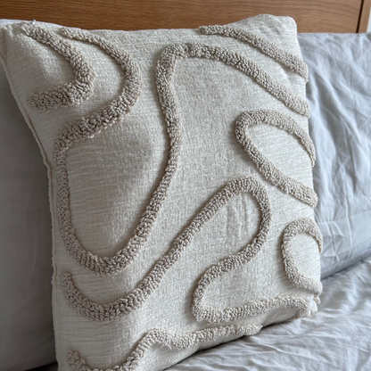 Textured pillow on a bed with a wooden headboard beige