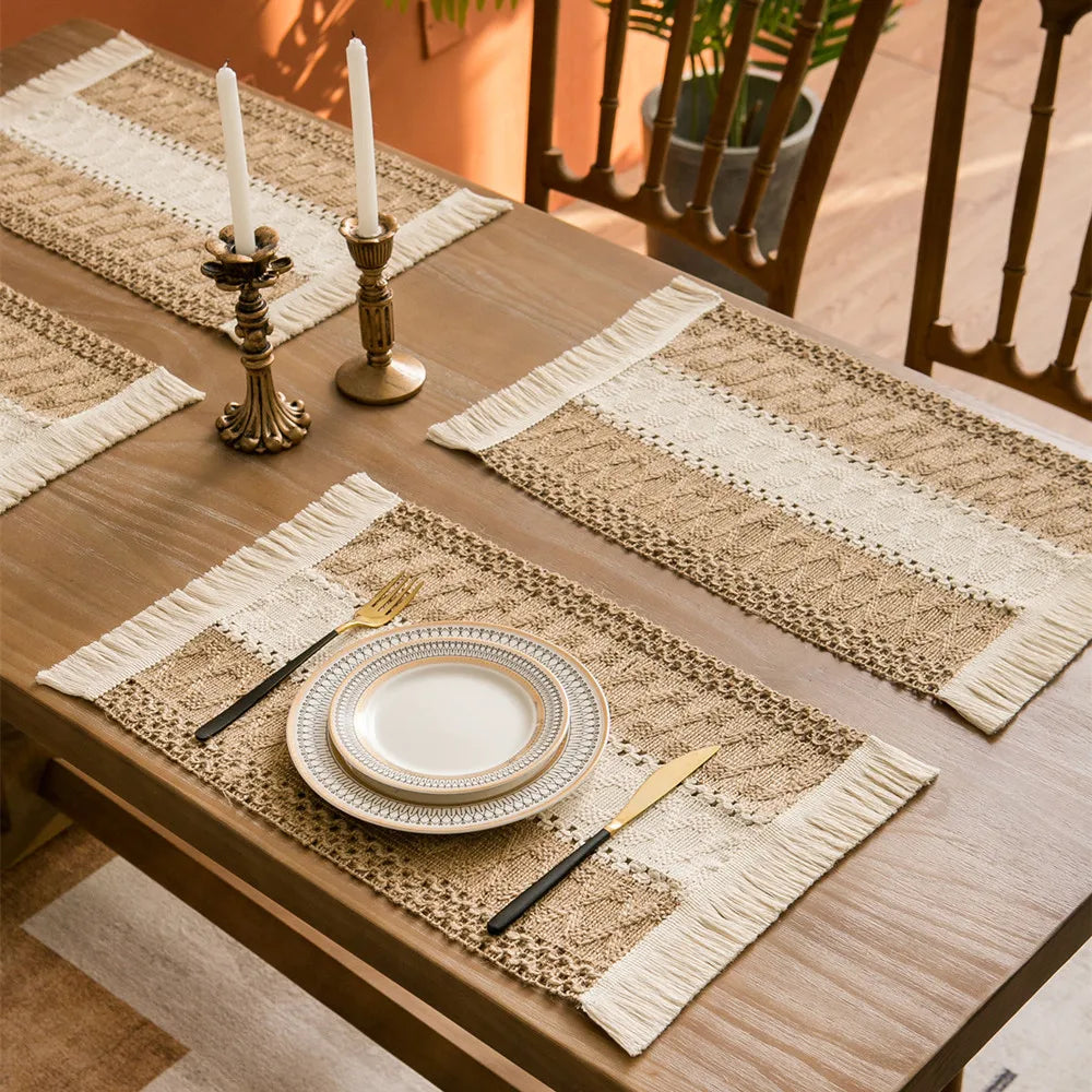 Dining table set with boho farmhouse placemats, plates and cutlery on a wooden table.