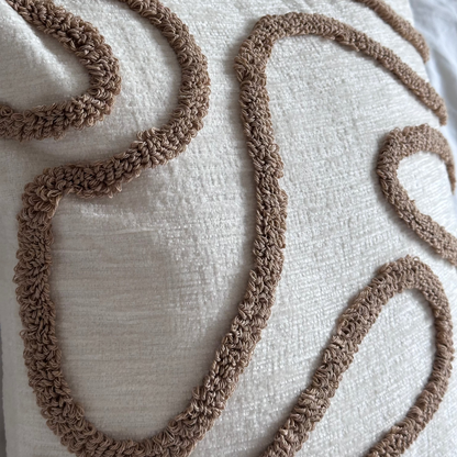 Decorative pillow with brown embroidered patterns on a wooden surface