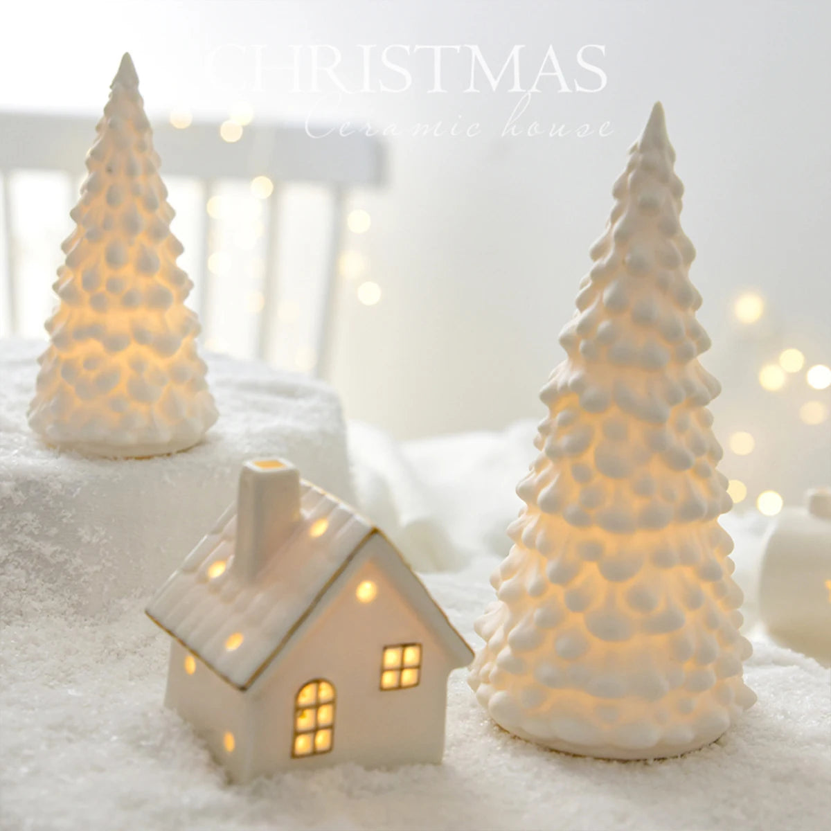 A set of ceramic Christmas houses with lights, designed to create a mini Christmas village scene, placed on a surface with snow and decorative lights.