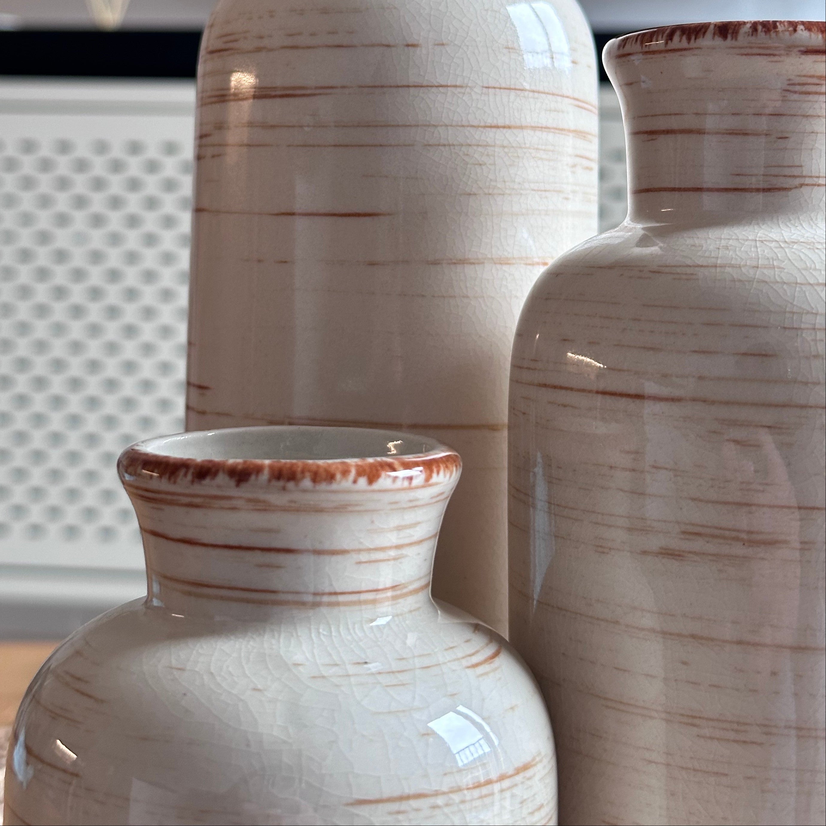 Three ceramic vases with brown stripes on a neutral background