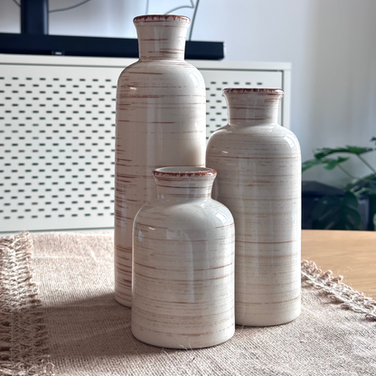 Three ceramic vases of different sizes on a textured surface with a blurred background