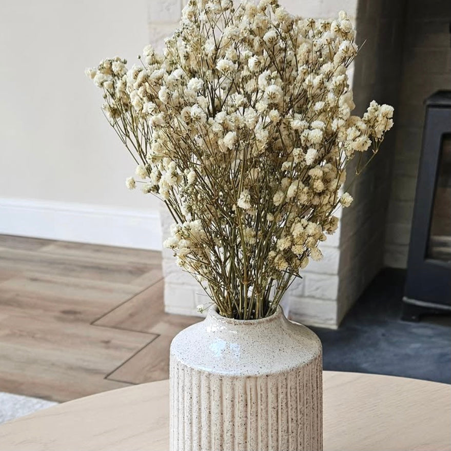Decorative vase with dried gypsophila flowers on a wooden surface