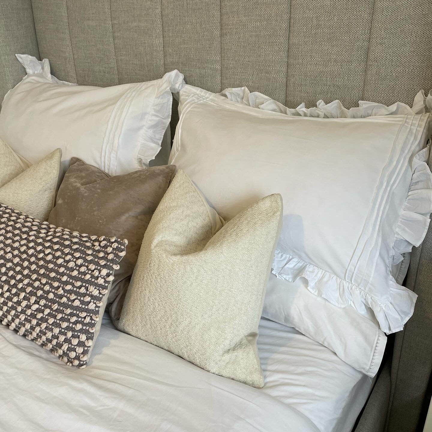 Neatly arranged pillows on a bed with a textured headboard.