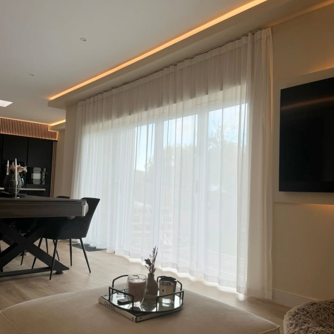 Modern living room with elegant tulle wave white curtains, a TV, and a coffee table.