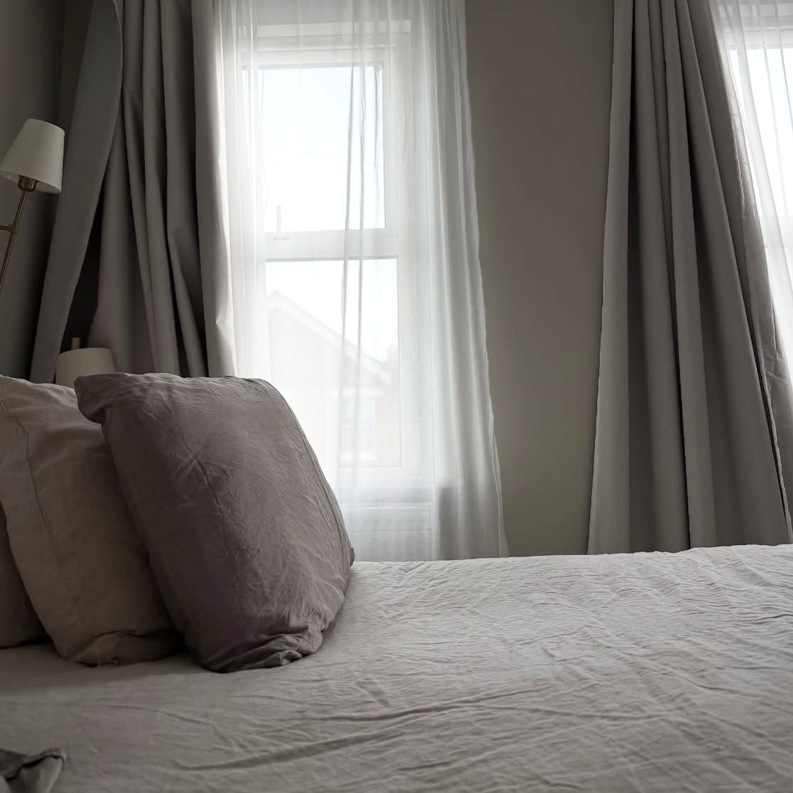 A neutrally styled bedroom setting, featuring elegant tulle wave curtains against a backdrop of sunshine.